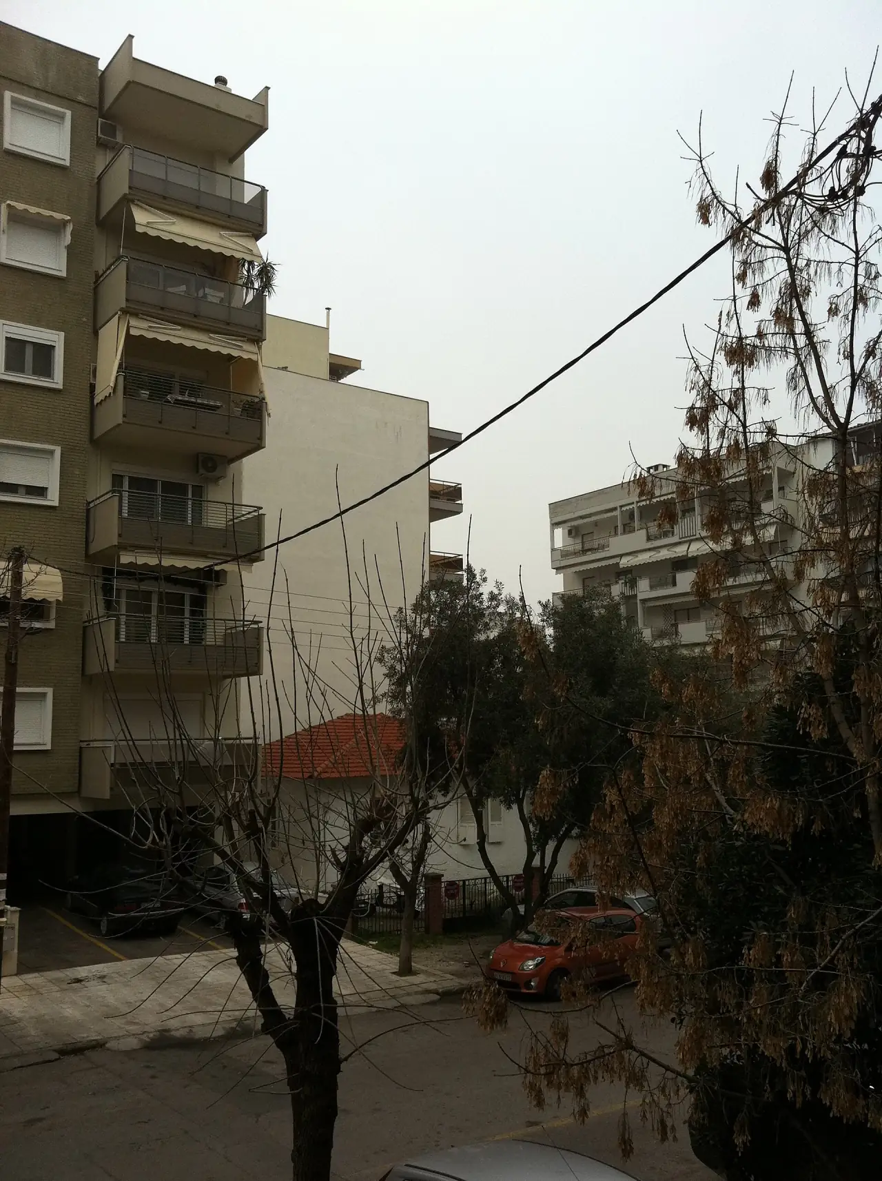 Γωνία δρόμου στην Καλαμαριά, με πολυκατοικία και ένα παλιό σπίτι δίπλα της.